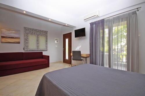 a bedroom with a bed and a red couch at Stamos Apartments and Studios in Vourvourou