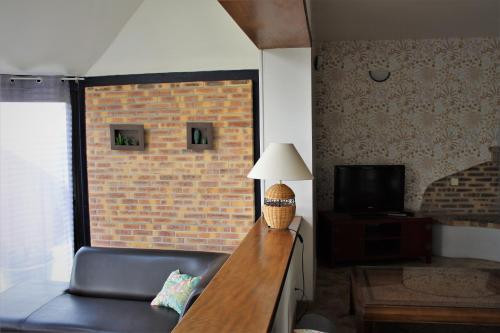 a living room with a table with a lamp and a couch at Gîtes Bellevue et Mascaret in Courtils