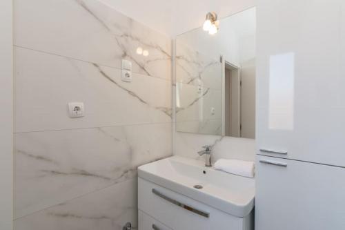 Un baño blanco con lavabo y espejo. en Tereza, city central modern apartment, en Novalja