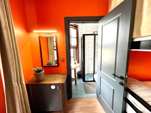 イスタンブールにあるHostel Le Bancのオレンジ色の壁の客室で、ドアとテーブルが備わります。