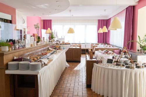 a restaurant with white tables and pink walls at HOTEL MARIA in Gramatneusiedl