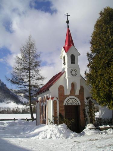 a church with a red and white steeple in the snow at Landgasthof Dorfstadl in Kössen