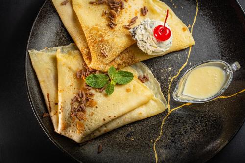 a plate of food with pancakes with a cherry on it at Hotel Moskva in Belgrade
