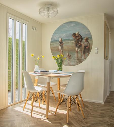 a dining room with a painting on the wall at ThuizInOuddorp Parel no 30 & Oester no 29 Verkoeling aan Zee in Ouddorp