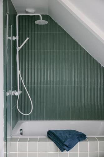 La salle de bains est pourvue d'une douche et d'un mur vert. dans l'établissement Le Duplex de Maison Passage, à La Trinité-sur-Mer