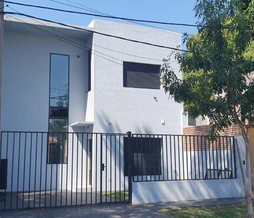 a white house with a black fence in front of it at Casa en La Florida a metros río in Rosario