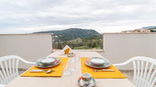 una mesa con platos y vasos en la parte superior de un balcón en Welcomely - Appartamento Nuraghe Tanca Manna, en Nuoro