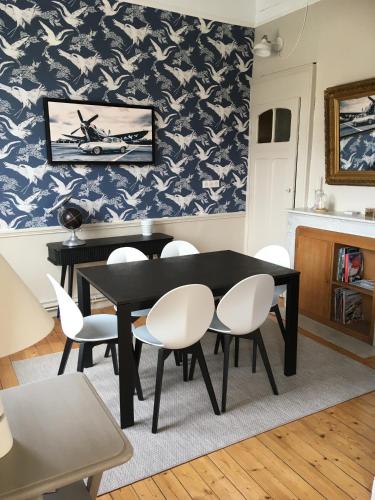 une salle à manger avec une table noire et des chaises blanches dans l'établissement Sans Adieu, à Wimereux