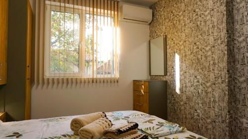 Schlafzimmer mit einem Bett und einem Fenster in der Unterkunft Апартамент Далия - Apartment Dalia in Warna
