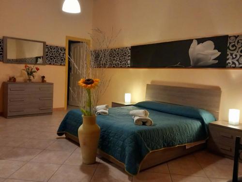 a bedroom with a bed and a vase with flowers in it at Villa Laura Apartment in Giardini Naxos