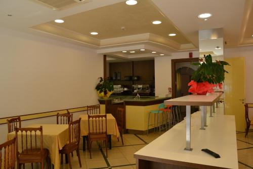 a restaurant with tables and chairs and a kitchen at Hotel Ariston in Misano Adriatico