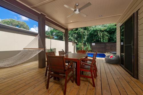 eine Terrasse mit einer Hängematte sowie einem Tisch und Stühlen in der Unterkunft Sea Change Villas in Rarotonga