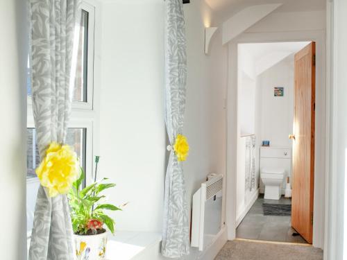 korytarz z białymi ścianami i żółtymi kwiatami w obiekcie Mews Cottage w mieście Tintagel