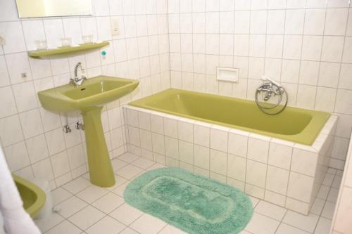 La salle de bains est pourvue d'une baignoire verte et d'un lavabo. dans l'établissement Aux Deux Clefs, à Marmoutier