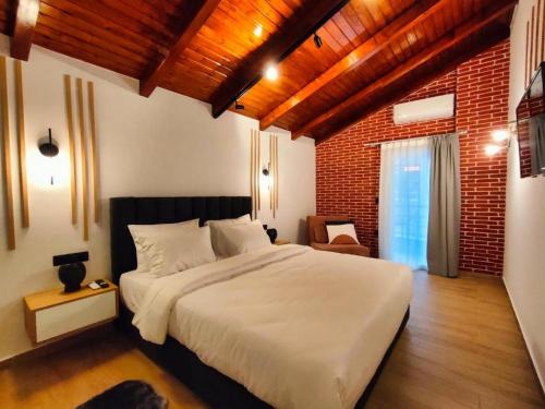 a bedroom with a white bed and a brick wall at Centro Urban Suites in Kalabaka