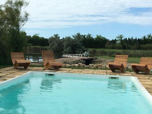 - une piscine avec 2 chaises et un foyer extérieur dans l'établissement Mas des jours heureux aigues mortes, à Aigues-Mortes