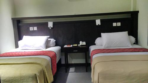 a room with two beds and a table between them at MAXI HOTEL KEDONGANAN in Kuta