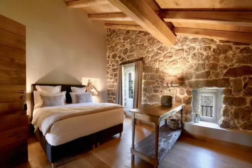 a bedroom with a bed and a stone wall at Maison Madamicella in Fozzano