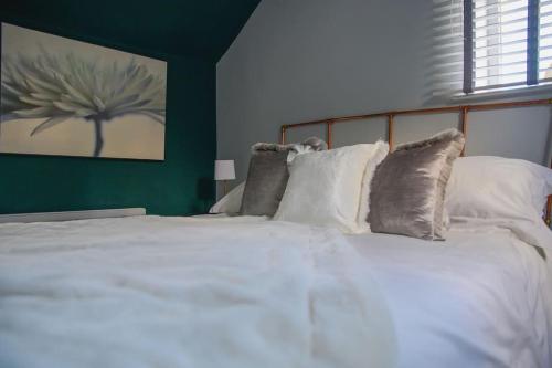 a bedroom with a white bed with a green wall at Cotswolds Corner Cottage in Moreton in Marsh