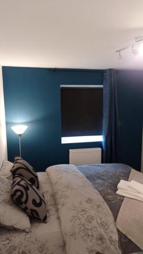 een slaapkamer met een bed met een blauwe muur bij love Romm in Londen