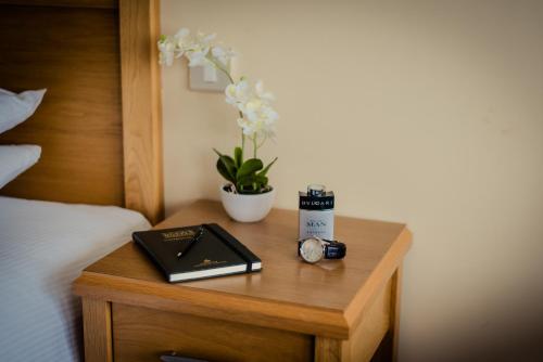 a table with a book and a clock on a bed at Rochestown Lodge Hotel in Dun Laoghaire
