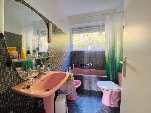 W łazience znajduje się różowa umywalka i różowa wanna. w obiekcie Panchika w mieście Oostduinkerke