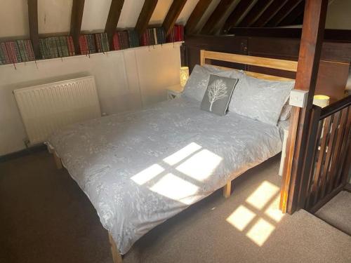 a bed in a room with the sun shining on it at Cosy Cottage next to Farmers Arms Country pub. in Gloucester