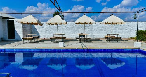 a group of tables and umbrellas next to a swimming pool at HARIYALI RESORT in Sardārgarh