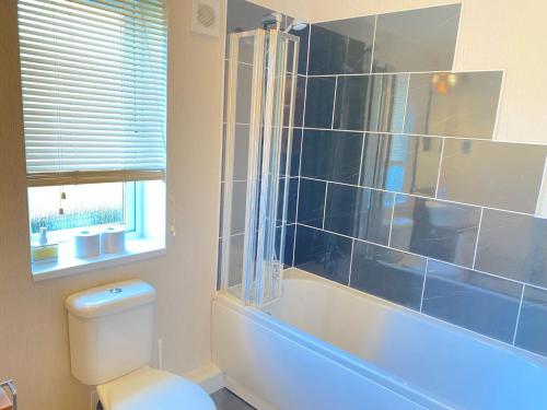 La salle de bains est pourvue d'une baignoire, de toilettes et d'une douche. dans l'établissement Dalis Den Lodge, à Bridlington
