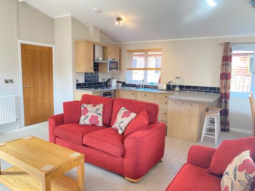 a living room with a red couch and a kitchen at Dalis Den Lodge in Bridlington
