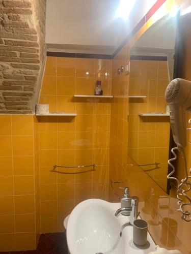łazienka z umywalką i żółtymi kafelkami w obiekcie Residenza Via Dante w mieście Gubbio