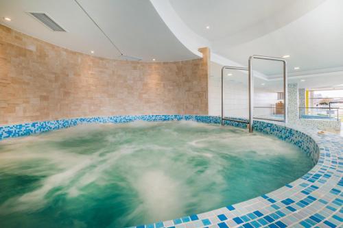bañera de hidromasaje en una habitación con azulejos azules y blancos en MF Club 218 Palazzo Wellness Apartment, en Siófok
