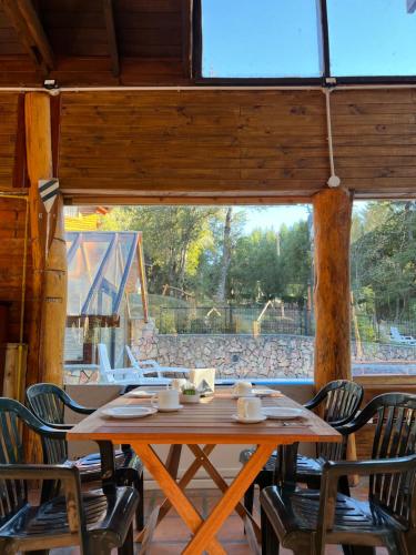 een houten tafel en stoelen in een kamer met een raam bij Portal del Manzano in Villa La Angostura