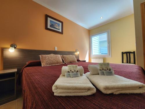 1 dormitorio con 1 cama grande y toallas. en Hostería Vertical Lodge en El Chaltén
