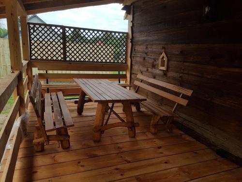a wooden porch with a picnic table and benches at Dom z bali. Chata Michal. in Białowieża