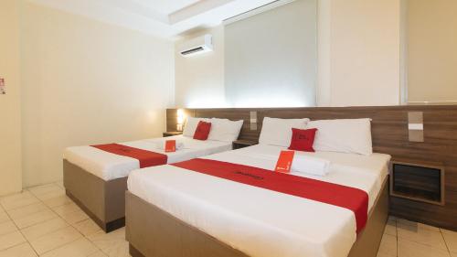 a hotel room with two beds with red pillows at RedDoorz at V Plaza Hotel Manila in Manila