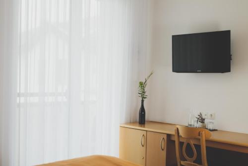 a room with a desk with a television on a wall at Weingut & Gästehaus zum Seeblick - Familie Sattler in Jois