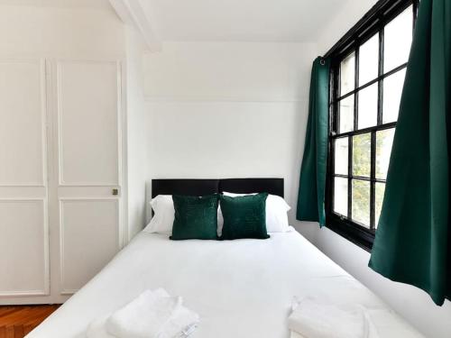 uma cama branca com almofadas verdes num quarto em Westgate House em Cardiff