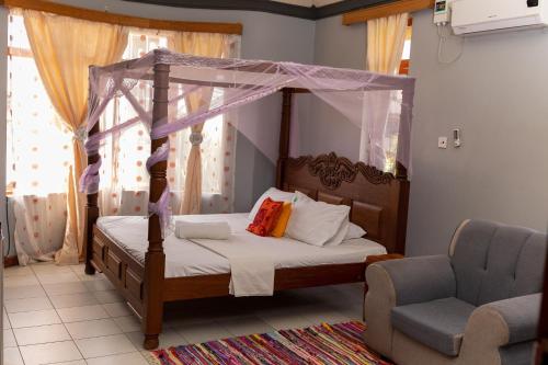 a bedroom with a canopy bed and a chair at tulia liqizo homestay in Mombasa