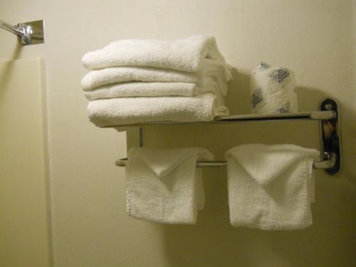 a pile of towels on a towel rack in a bathroom at Value Inn Motel - Milwaukee Airport South in Oak Creek