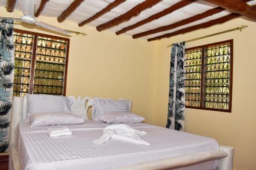 a bedroom with a bed with white sheets and windows at Private room in a villa in Diani Beach