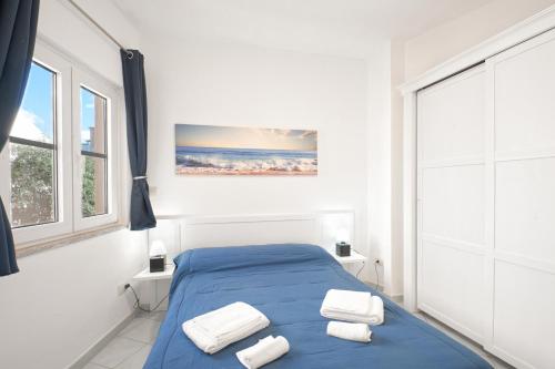 ein Schlafzimmer mit einem blauen Bett und Handtüchern darauf in der Unterkunft Calarossa Bay in Isola Rossa