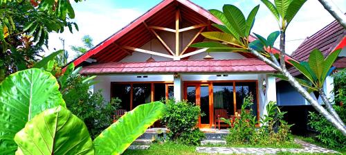 a house with a red roof in a forest at Novia Guest House Lombok-Tetebatu in Tetebatu