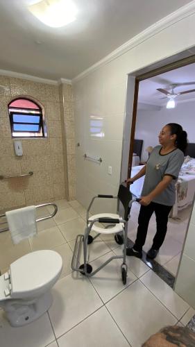 a woman standing in a bathroom with a chair at Hotel Real São Lourenço in São Lourenço
