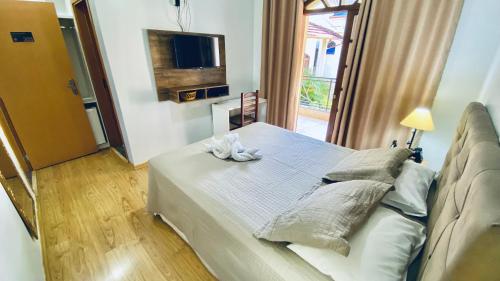 a bedroom with a bed with a television and a window at Hotel Real São Lourenço in São Lourenço