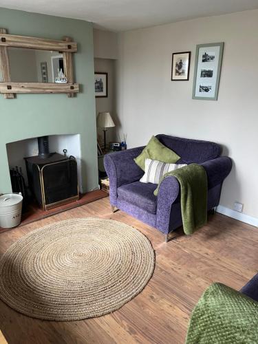 a living room with a purple couch and a rug at Turning Tides Holiday Cottage in Great Yarmouth