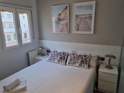 a bedroom with a white bed with two windows at Sitges Oasis in Sitges
