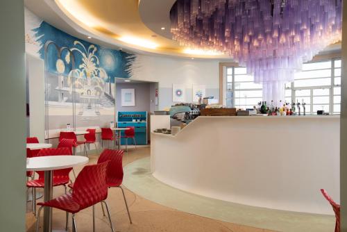 a restaurant with red chairs and tables and purple chandeliers at The Midland in Morecambe