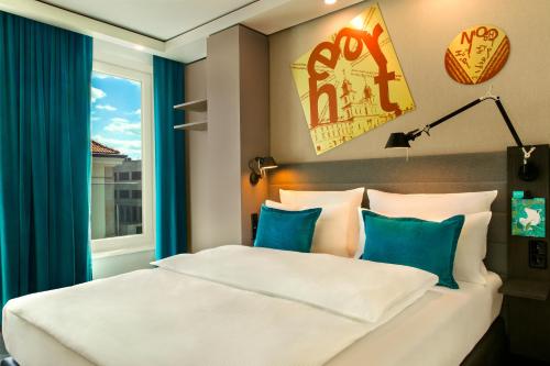 a bedroom with a bed with blue curtains and a window at Motel One Warsaw-Chopin in Warsaw