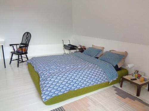 1 dormitorio con 1 cama y 1 silla en la maison blanche, en Cléden-Cap-Sizun